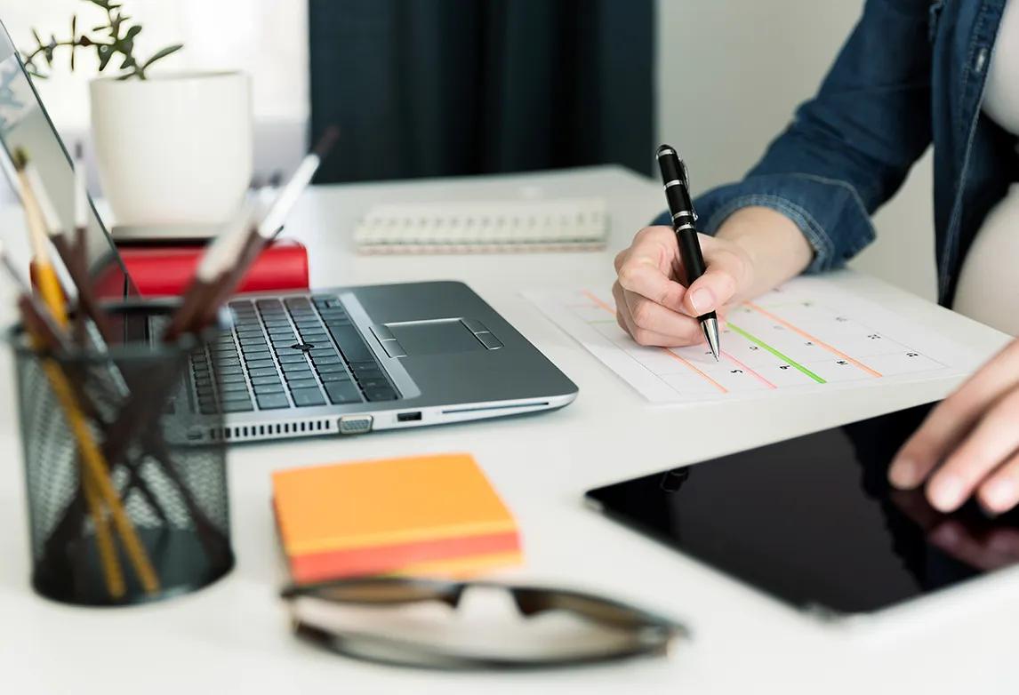 A woman writes on a calendar to keep on track with her time management