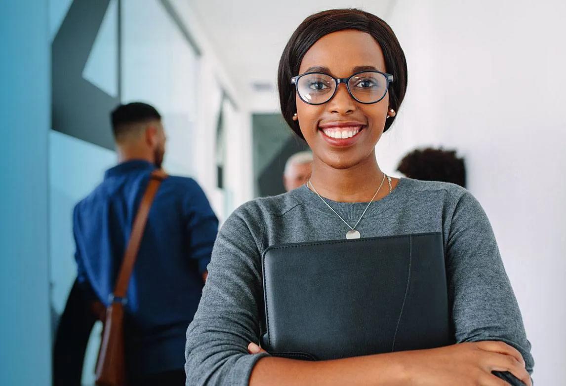 A woman smiles whiles clutching a folder