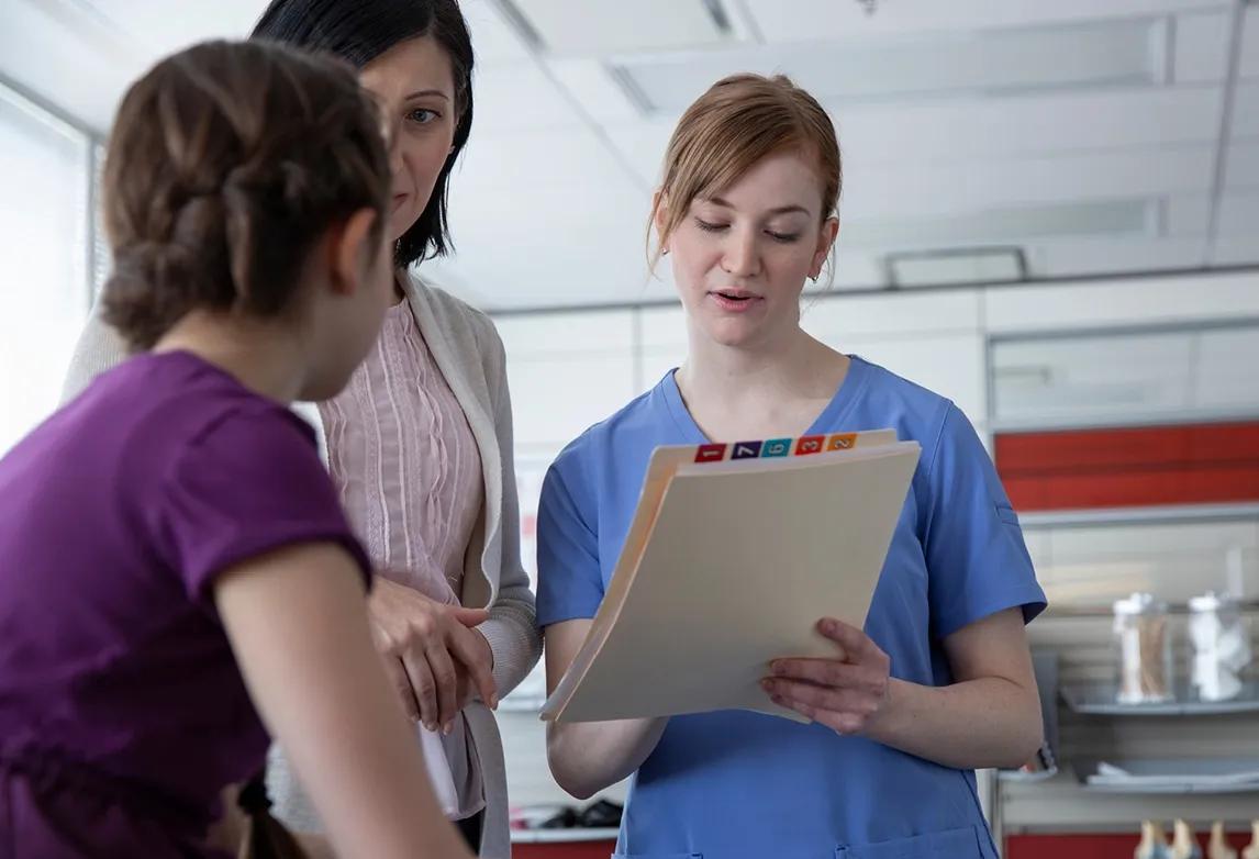 A medical records analyst reviews charts with two patients