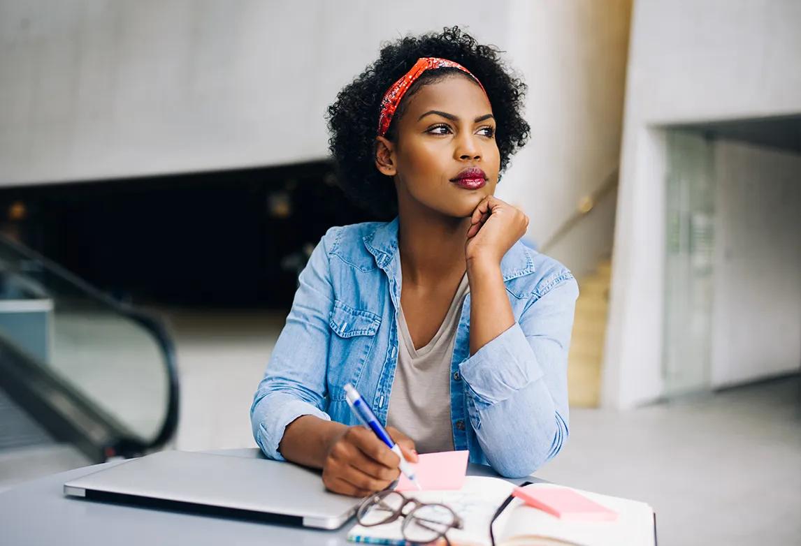 A woman sits at a table with her calendar, tracking how to keep to her schedule and learn time management.