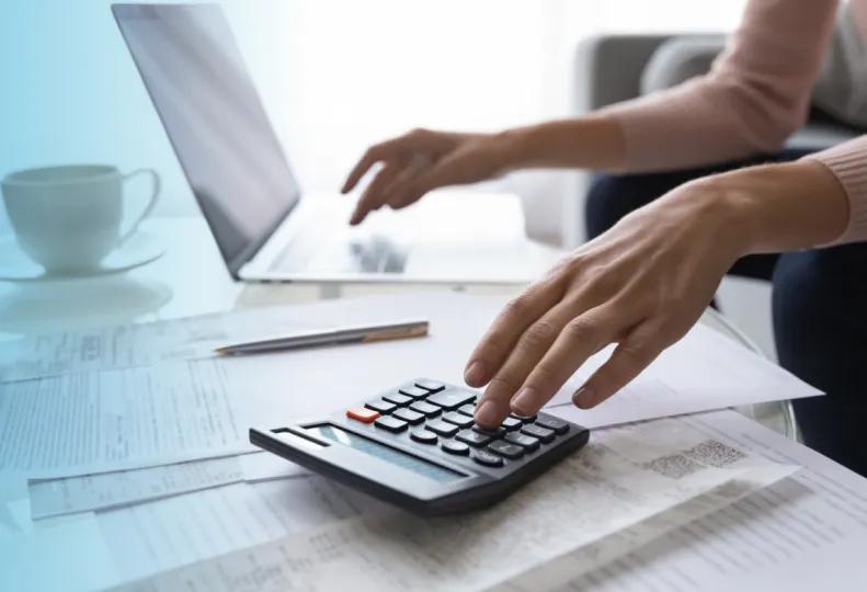 a healthcare accounting professional adding numbers on a calculator after earning a healthcare accounting degree